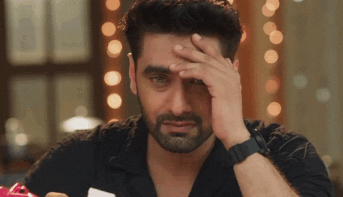a man with a beard is covering his face with his hand and crying .