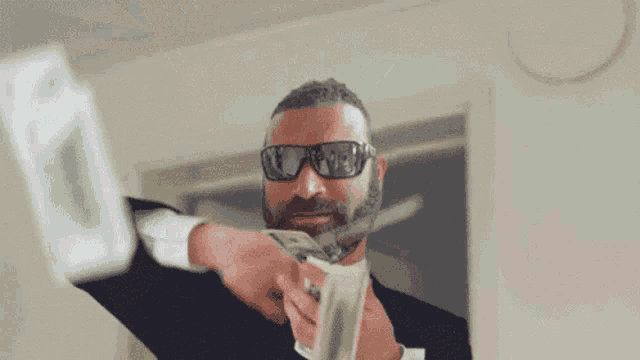 a man in sunglasses is holding a pile of money