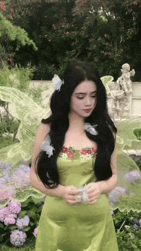 a woman in a green dress with butterflies in her hair is standing in a garden