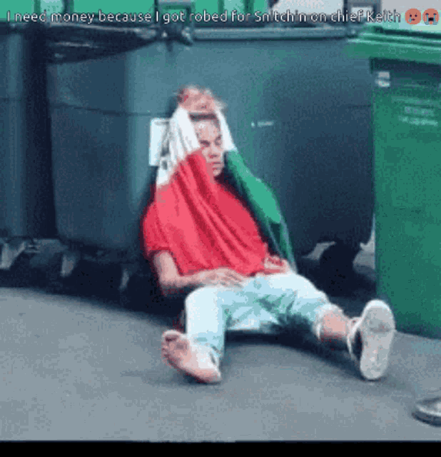 a man in a red shirt is laying on the ground next to a green trash can with the words i need money because