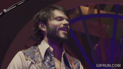 a man with a beard is singing into a microphone with the website gifrun.com in the corner