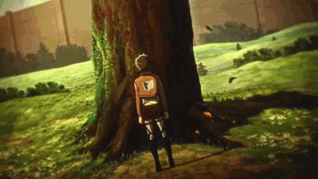 a man standing next to a tree with a backpack that has the letter m on it