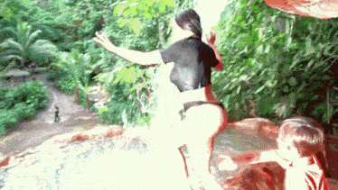 a woman in a bikini is standing on a rock near a waterfall