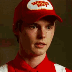a man wearing a wiener hut hat and striped shirt