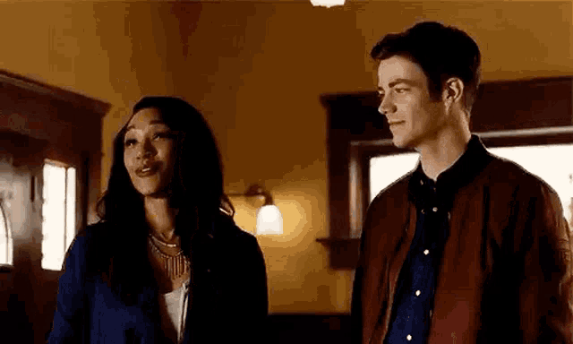 a man and a woman are standing next to each other in a room and talking .