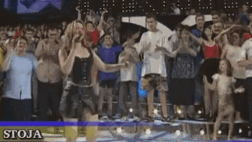 a group of people dancing in front of a sign that says stoja
