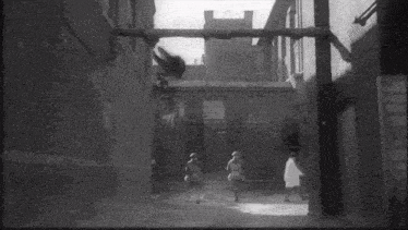 a black and white photo of people walking down a street with a sign that says ' a ' on it