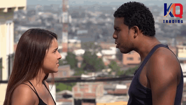 a man and a woman are looking at each other with the kn trading logo in the background