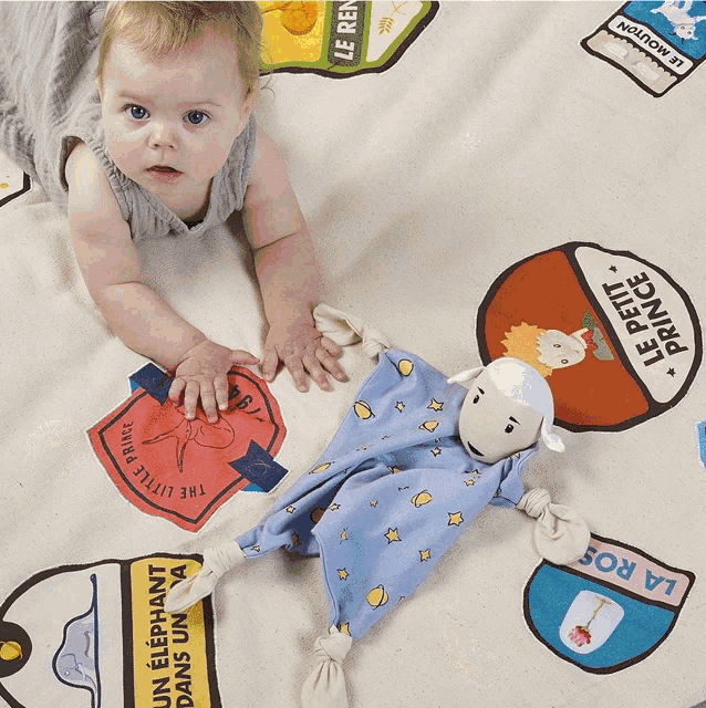 a baby laying on a blanket with a stuffed animal that says le petit prince on it