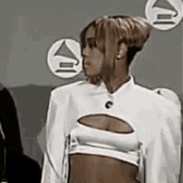 a woman in a white crop top with a cut out in the middle is standing in a room .