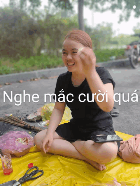 a woman sits on a yellow tarp with the words nghe mac cuoi qua written above her
