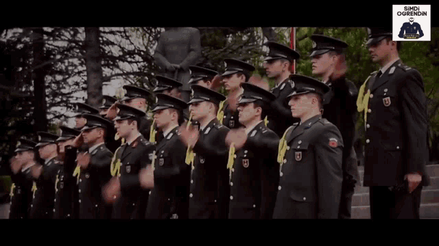 a group of men in military uniforms salute in front of a sign that says ' sireni ogrenon '