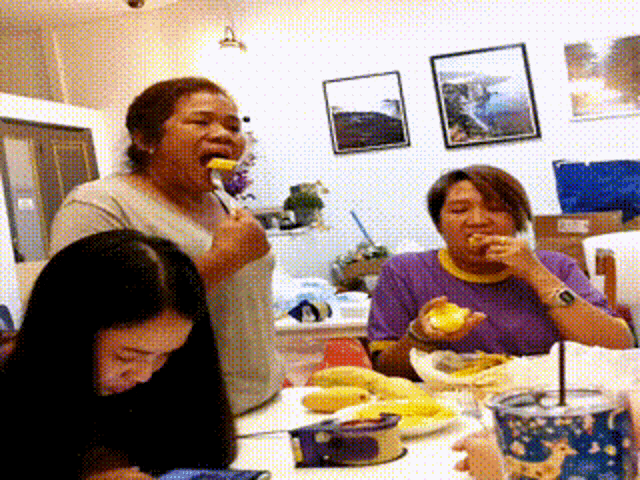 a woman in a purple shirt is eating a piece of food