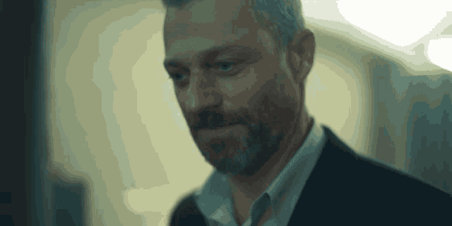 a man with a beard is wearing a suit