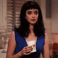 a woman in a blue dress is holding a paper cup .