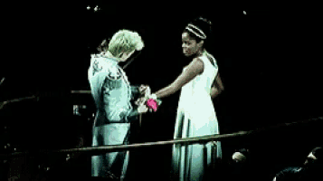 a man and woman are holding hands on a stage