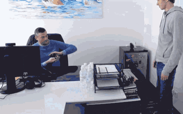 a man sitting in front of a computer with a bottle of water on the desk