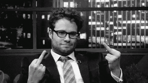 a man in a suit and tie is making a middle finger gesture .