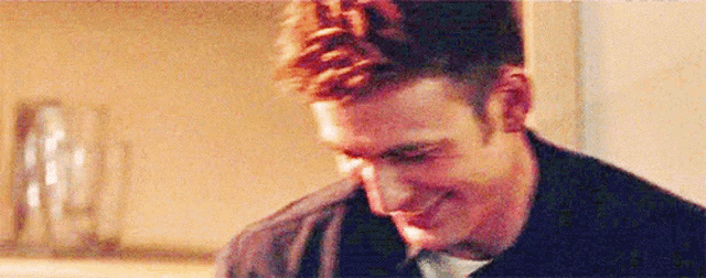 a close up of a man 's face smiling while looking down .