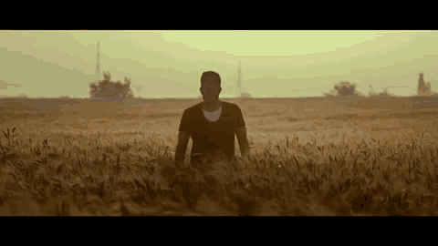 a man is kneeling in a field of tall grass .