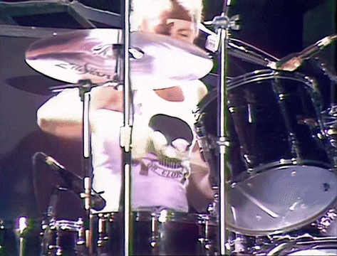 a man playing a drum set with a shirt that says guns n roses