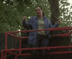a woman in a blue jacket is standing behind a red fence
