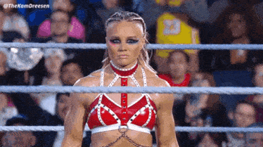 a woman is standing in a wrestling ring with a crowd behind her .