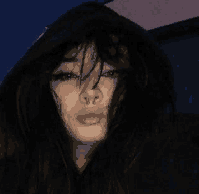 a girl with a nose ring is wearing a black hoodie and has long hair .