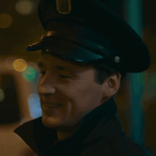 a close up of a man wearing a police hat and smiling