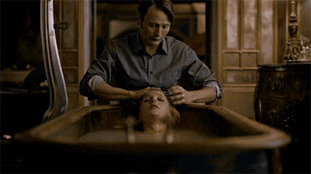 a man is touching a woman 's head in a bathtub