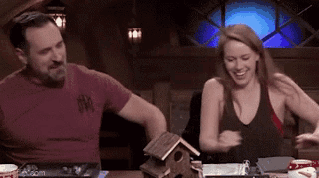 a man and a woman are sitting at a table laughing .