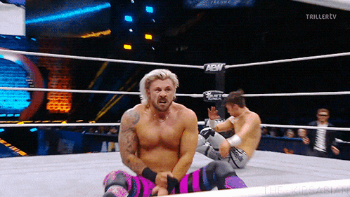 two men are wrestling in a ring with a sign that says new