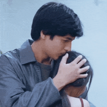 a man kisses a woman on the forehead while she looks on