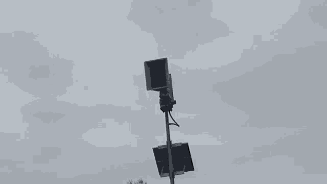 a large speaker on top of a pole with a solar panel attached