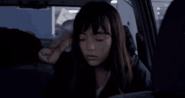 a woman is sitting in the back seat of a car with a stuffed animal on her head .