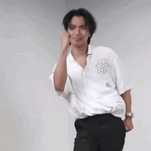 a man in a white shirt and black pants is dancing and making a funny face .