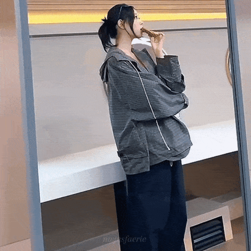 a woman is standing in front of a mirror eating a piece of food .