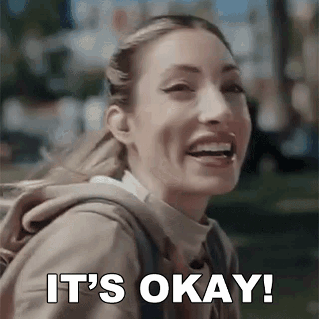 a woman with a backpack is smiling and saying it 's okay !