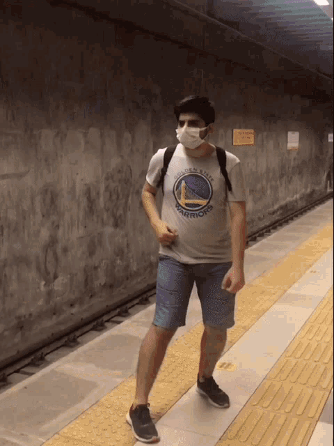 a man wearing a mask and a golden state warriors t-shirt