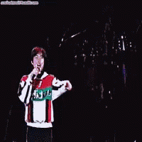 a man is singing into a microphone while wearing a red and green sweater