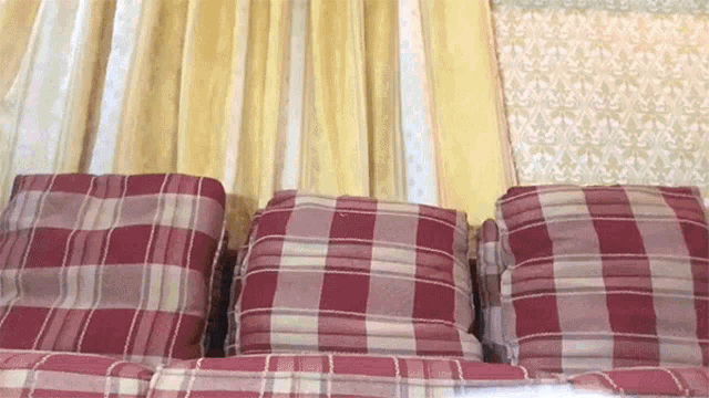 a row of plaid pillows are stacked on top of each other on a bed
