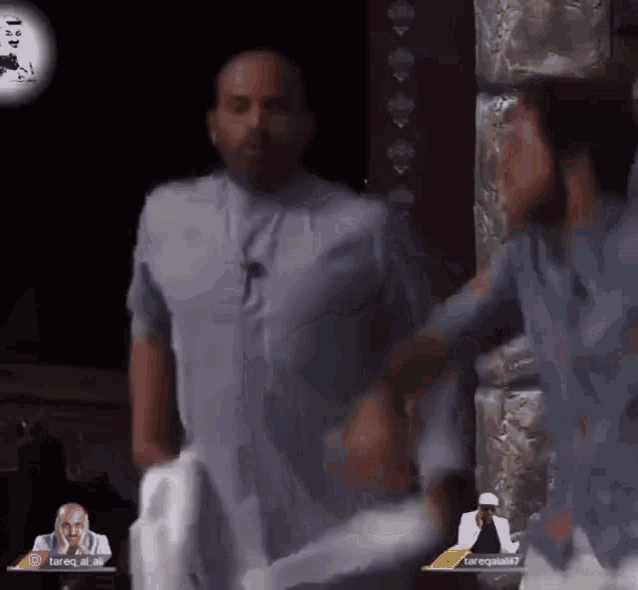 a man in a blue shirt is standing next to a man in a white shirt with the name tareq on it