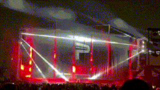 a crowd watching a concert with a large p on the stage