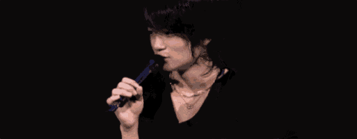 a man is singing into a microphone with a black background .