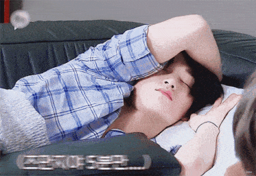 a man in a blue plaid shirt is sleeping on a couch