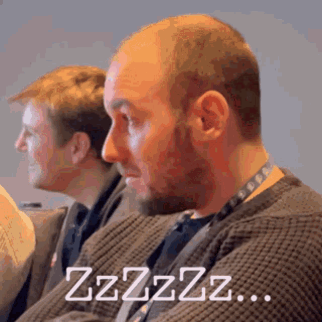 a man with a beard is sitting next to another man with the words zzzzz written on the bottom