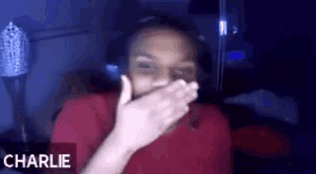 a person is covering their mouth with their hand while wearing headphones and a red shirt .