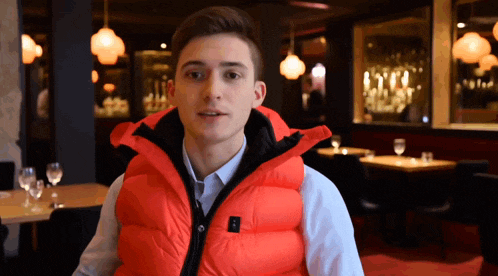 a young man wearing a bright orange vest stands in front of a restaurant
