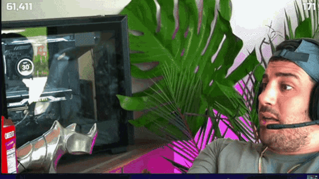 a man wearing headphones is looking at a computer monitor with the number 61,411 on it