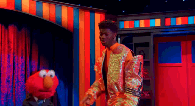 elmo is standing next to a man in a suit on a stage